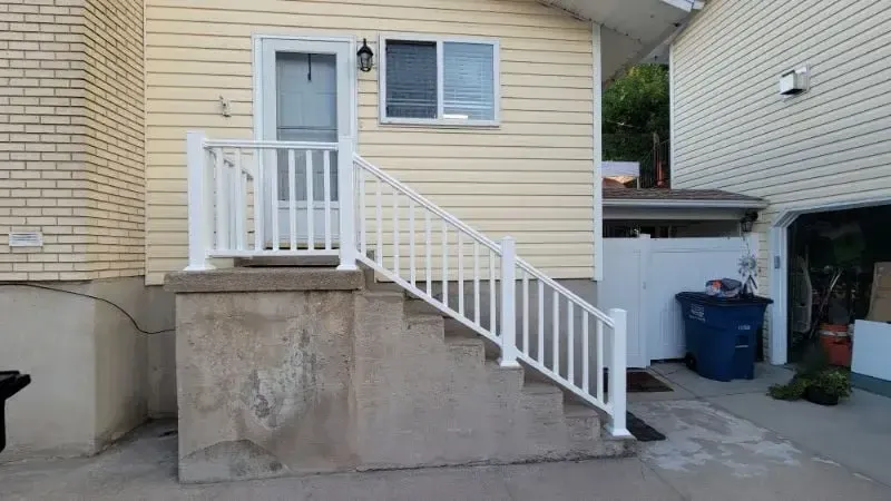 White metal handrail installed along concrete entry steps