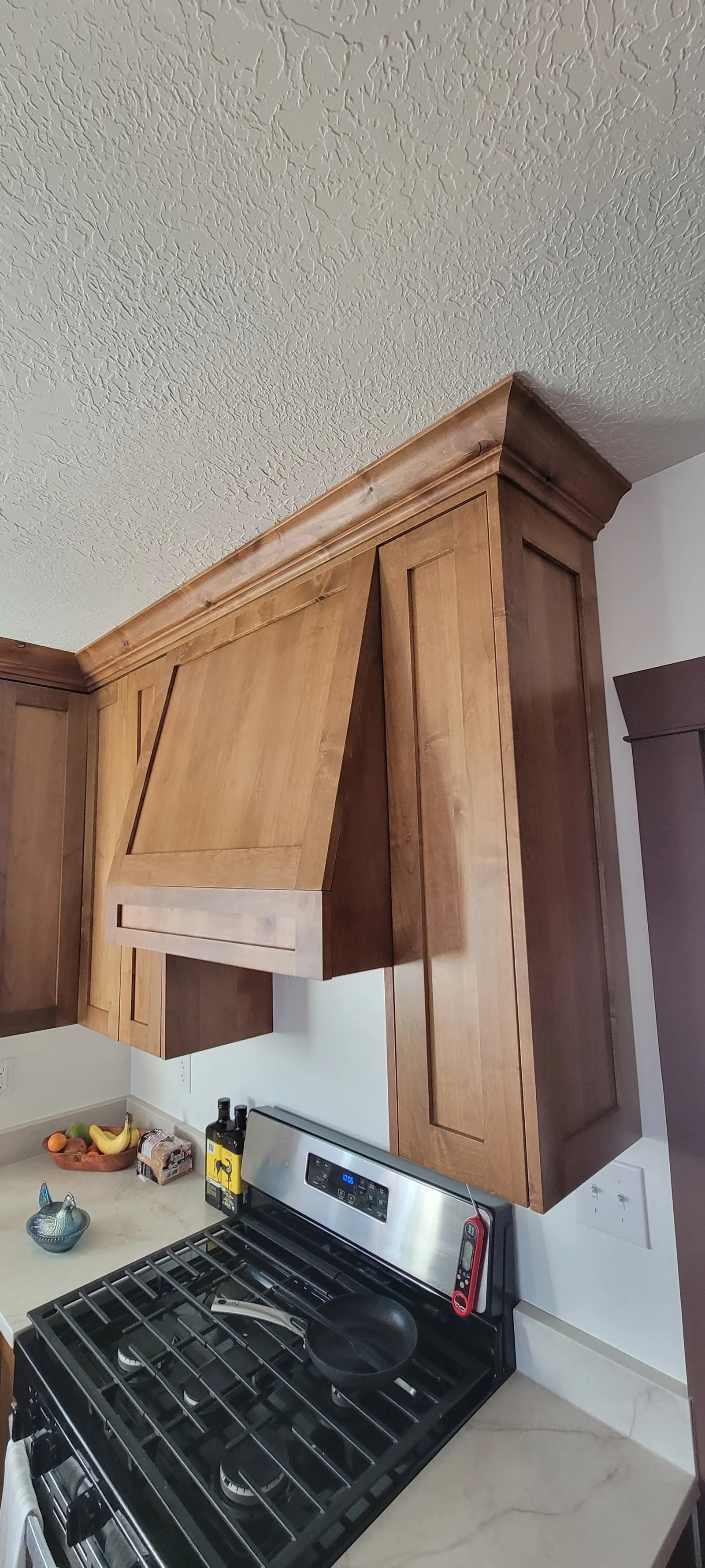 Stained wood cabinet and hood surround installed above a gas range